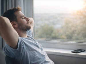 Uomo rilassato alla finestra con smartphone